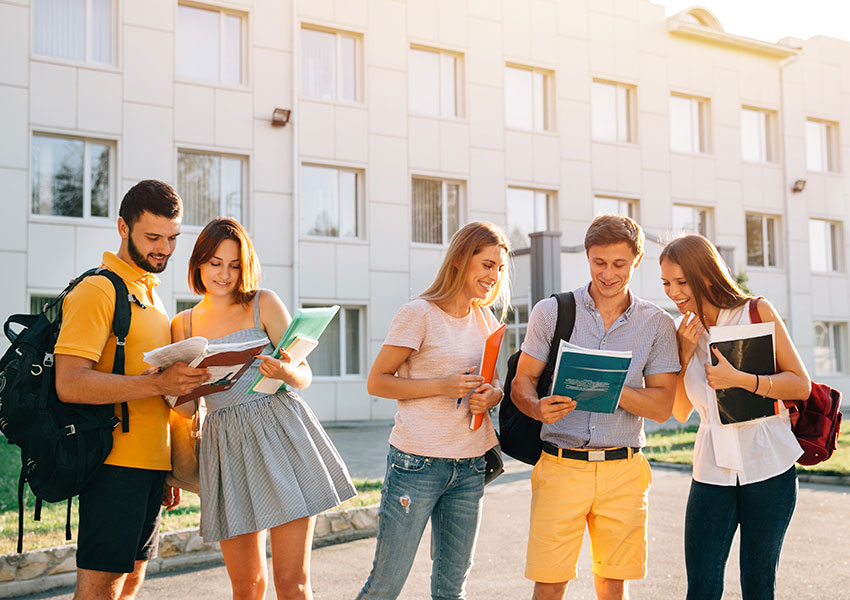 Classmates Group Of Cheerful Students Teenagers  With Note Books Are Studying Outdoors At Campus