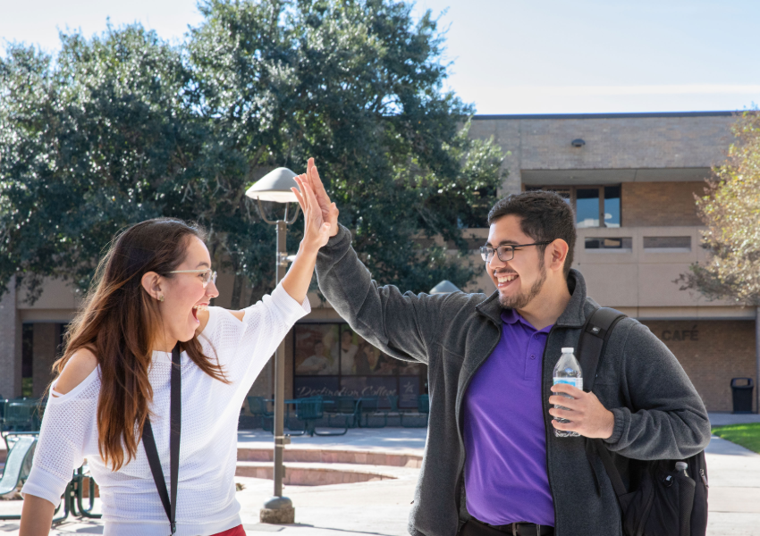 Two students high fiving the courtyard