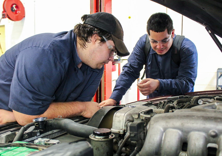 two automotive students working under the hood of a car
