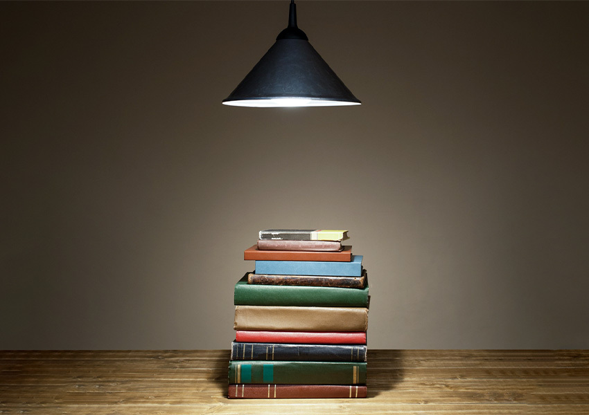 stacked books on a desk with a spotlight directed on them