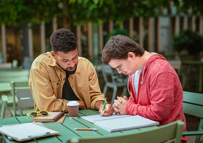Guy helping guy with writing