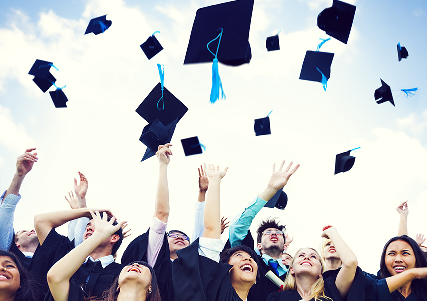 graduates in cap and gown throwing hats in the air