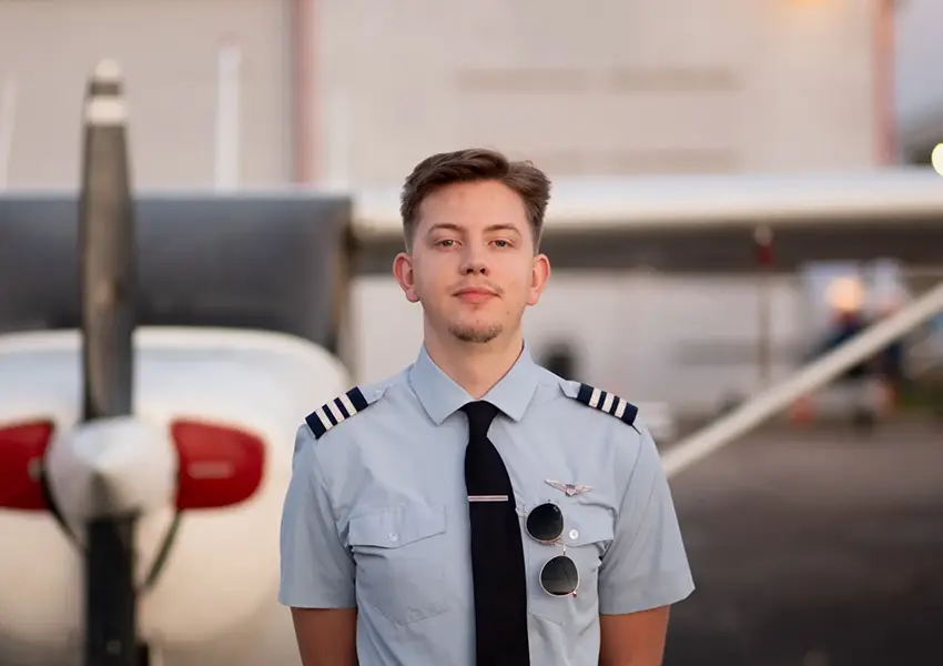 Professional pilot student and certified flight instructor standing in fron of a plane