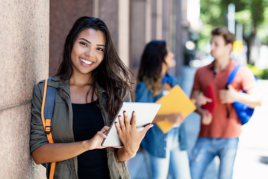 Young Mexican-American student smiling and holding a notebook