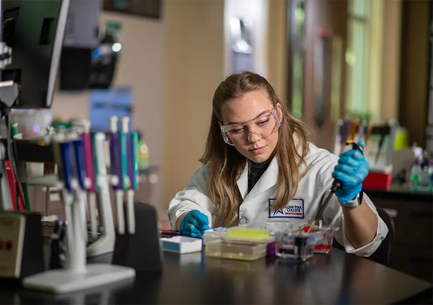 Student in a lab coat using a pipette