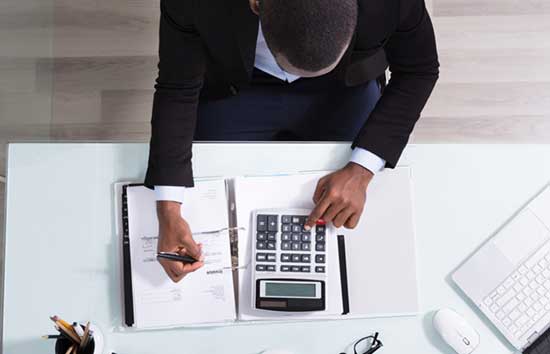 Man using a calculator and taking notes