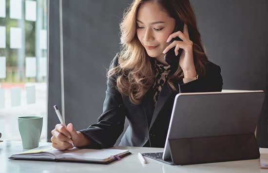 Woman taking notes while on the phone