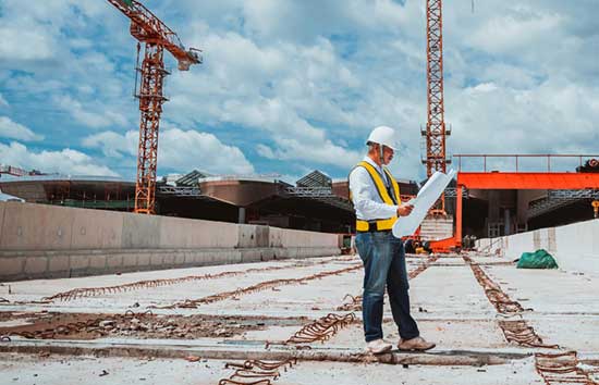 Man inspecting blueprints at a construction site