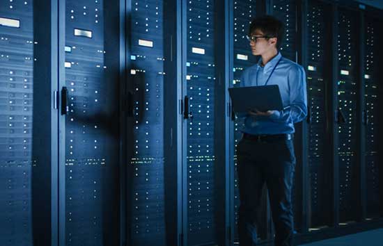 Man walks through a server room with a laptop