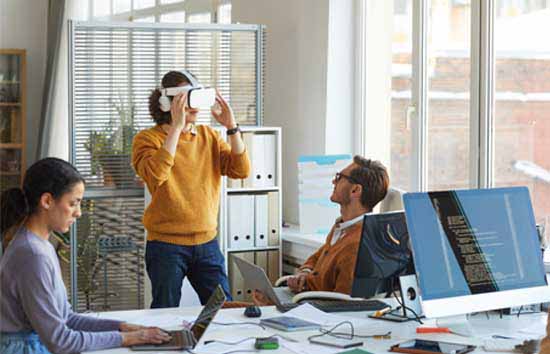 A woman wearing a VR headset next to a colleague