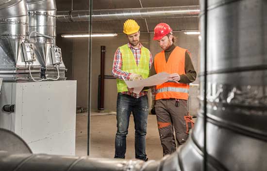 Two men in hardhats looking at their notes