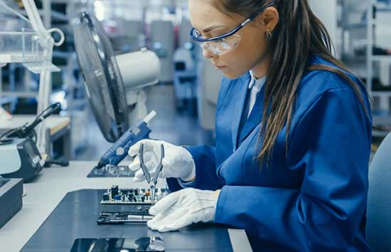 Woman working on a PCB with pliers