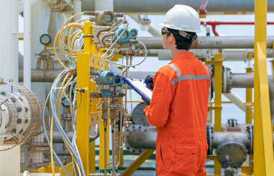 Worker in a hard hat standing in front of various tubing