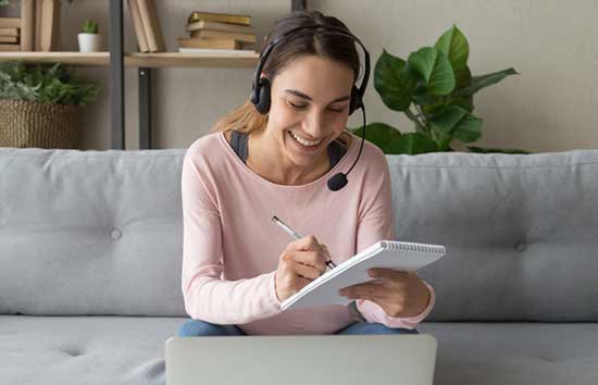 Woman wearing a headset and taking notes on her notepad