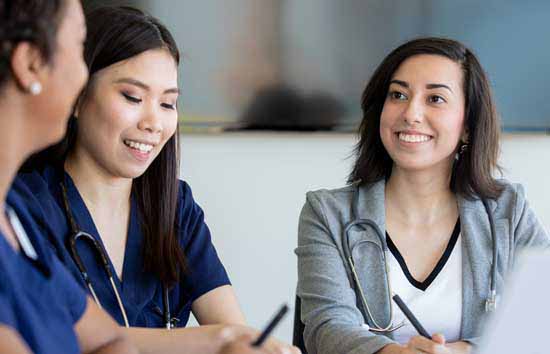 Three women with stethoscopes conversing