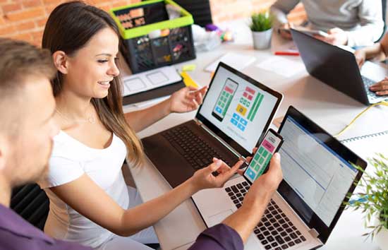 A man and woman looking at an app design on their phone