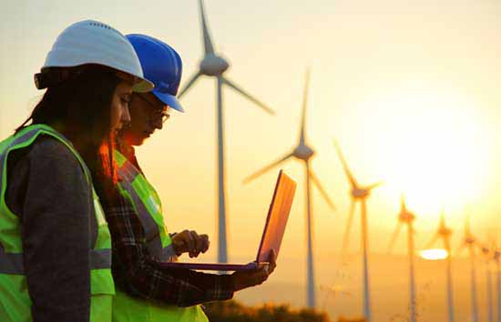 Two people on a laptop in front of windmills