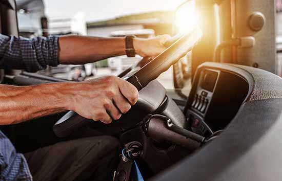 A man gripping a large steering wheel