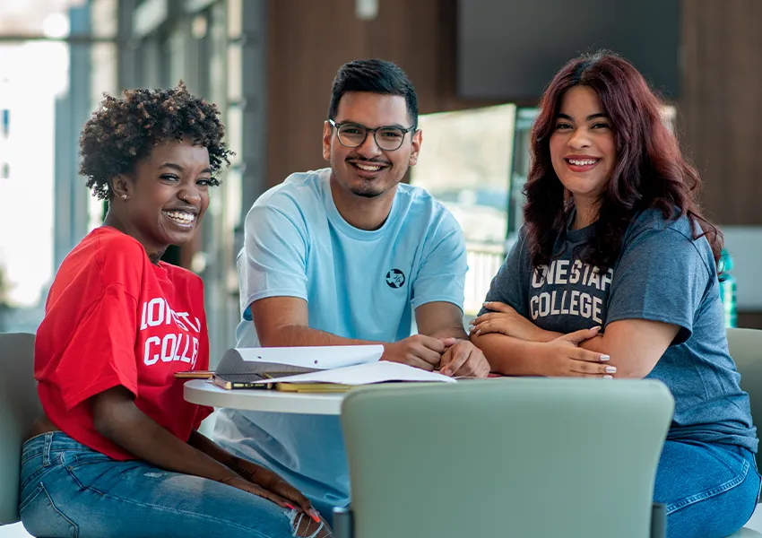 3 smiling students at a table