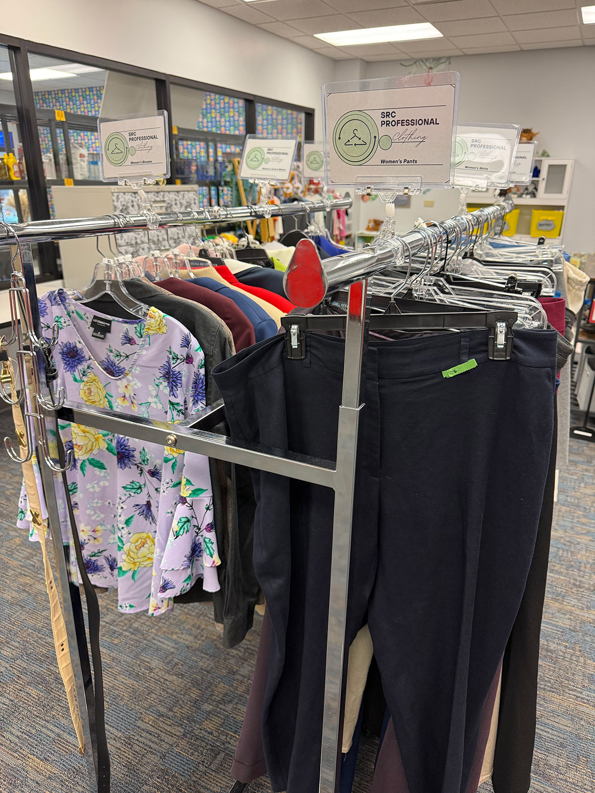 Wide view of the Career Closet. There are several racks of professional clothing for women and fitting rooms to try on items.