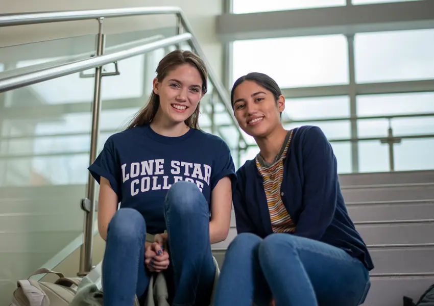 2 female students sitting on the stairs