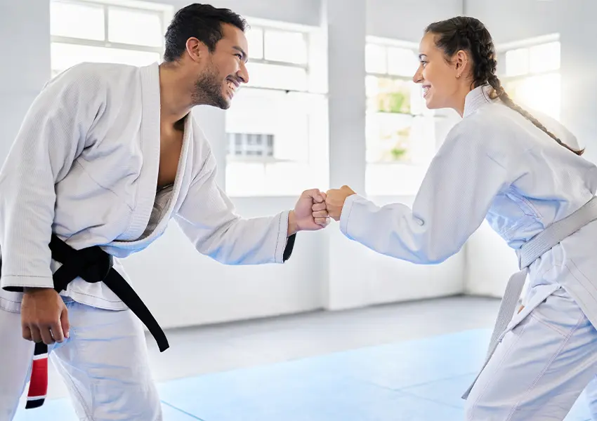 A man a woman wearing gi and fistbumping