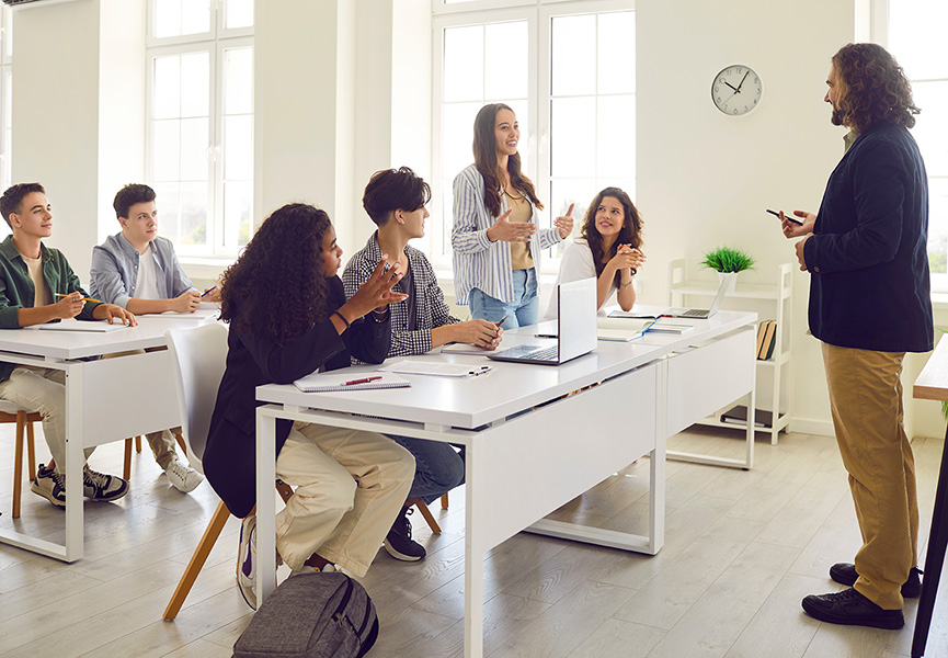 Bright classroom with college students facing the instructor on the right hand side of the photo. 