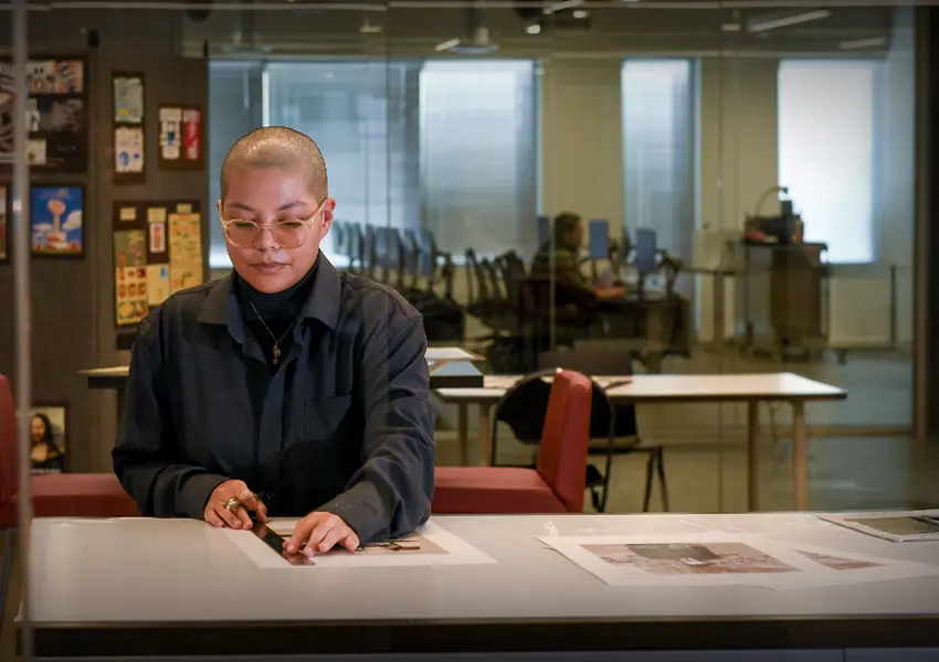 3 students and a professor handling a glowing hot metal cube in an industrial setting