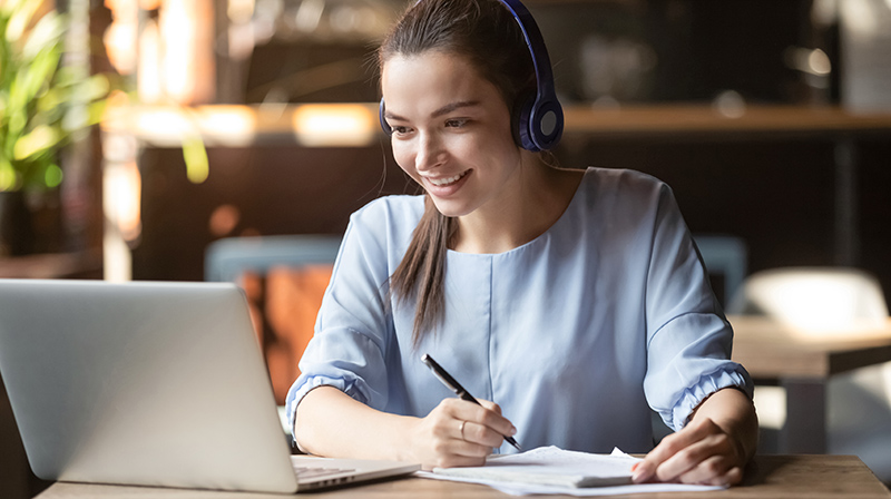 Female student with headphones on her laptop 